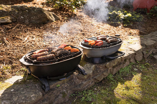 PK Grills PKGO with FlipKit, portable outdoor mini grills with sausages, vegetables, and smoke on grill grates for outdoor cooking and camping.