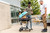 PK Grills The All New Original PK300AF Grill & Smoker - Teal, outdoor grilling scene with friends enjoying a barbecue on patio.