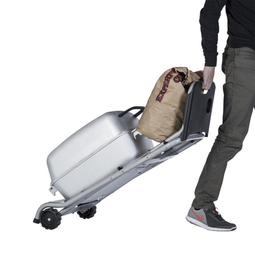 PK Grills The Original PKTX Grill & Smoker - Classic Silver, a portable outdoor grill and smoker with a metallic silver finish, being transported on a wheeled cart by a person.
