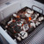 PK Grills The PK Heavy Duty Charcoal Basket, a heavy-duty metal basket filled with charcoal briquettes burning with red-hot embers inside a grill.