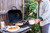 PK Grills The PK360 Grill & Smoker - Classic Silver, outdoor grilling with a person cooking food on a barbecue grill in a backyard setting.