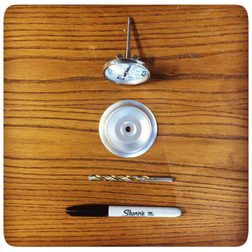 Tel-Tru The PK BBQ Thermometer by Tel-Tru, disassembled with stainless steel probe, metal base, black Sharpie marker, and drill bit on a wooden surface.